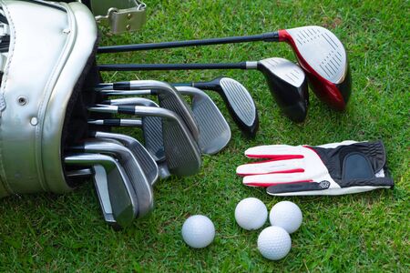 Closeup old golf bags on green. Set of golf clubs over green field background. の写真素材