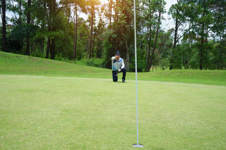 Blurred golf player at the putting green hitting ball into a hole. Golfer playing golf in beautiful golf course in thailand.の写真素材
