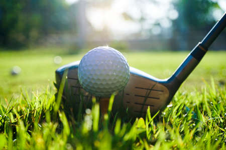 Golf club and ball on tee in grass. Golf balls on the golf course with golf clubs ready for the first short. In the morning, with the beautiful light. Sports that people around the world play in the holidays.の写真素材
