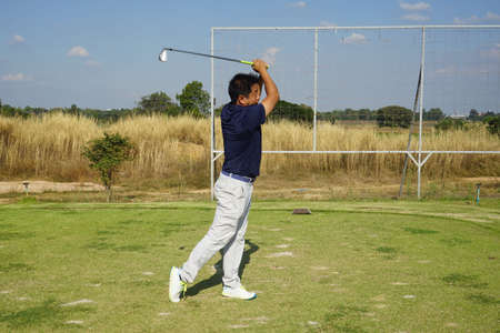 Golfer playing golf in the evening golf course, on sun set evening time. Man playing golf on a golf course in the sun.の写真素材