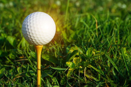 Golf ball on tee in the evening golf course with sunshine background. Golf ball on the green with warm tone and sunset.の写真素材