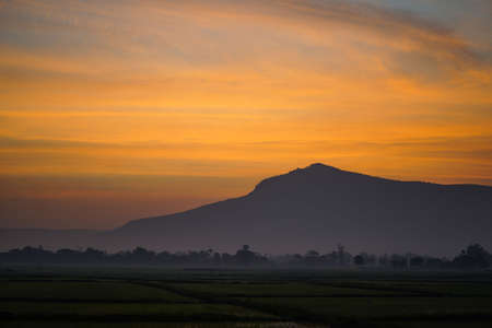 Golden morning sky in winter, misty high mountain background. Silhouette hills and misty in the morning at Chaiyaphum,Thailand.の写真素材