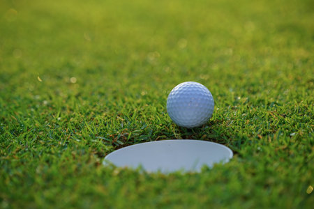 The ball at the hole on the golf course. Golf ball putting on green grass near hole golf to win in game at golf course with blur background.の写真素材