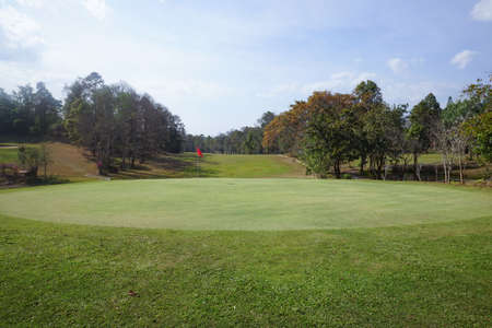 Background of evening golf course has sunlight shining down at golf course in Thailand. Nice scenery on a golf course at a late summer afternoon.の写真素材