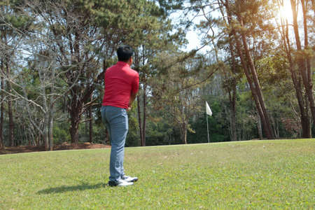 Blurred golfer playing golf in the evening golf course, on sun set evening time. Man playing golf on a golf course in the sun.の写真素材
