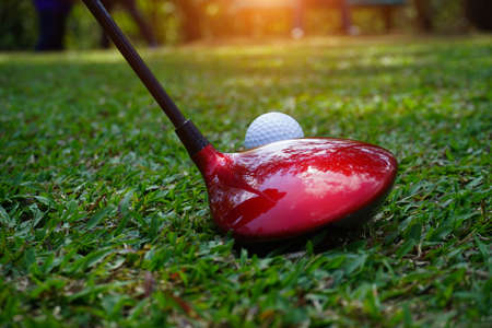 Golf club and golf ball close up in grass field with sunset. Golf ball close up in golf coures at Thailand.の写真素材