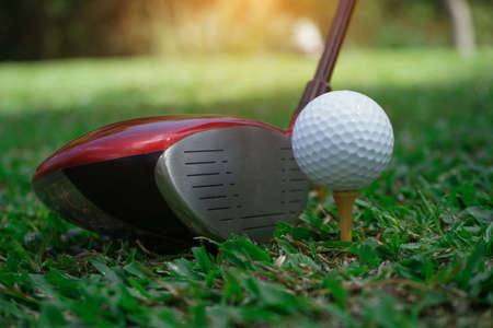 Golf club and golf ball close up in grass field with sunset. Golf ball close up in golf coures at Thailand.の写真素材
