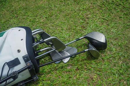 Closeup old golf bags on green. Set of golf clubs over green field background.の写真素材