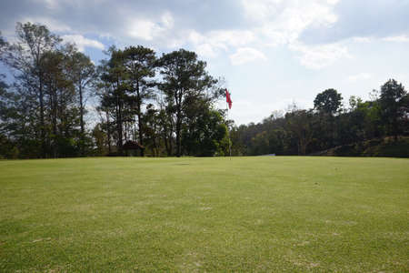 Landscape of a beautiful golf course at the sunset in the countryside. Red flag at the golf course in sunrise time.の写真素材