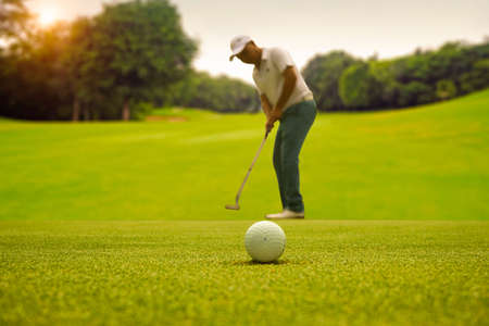 Silhouette male golfer putting golf ball on the green golf, lens flare on sun set evening time.の写真素材