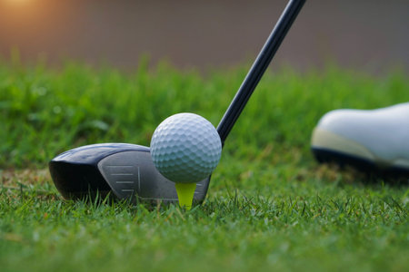 Golf club and golf ball on tee close up in grass field with morning sunshine. Ready for golf in the first short.の写真素材