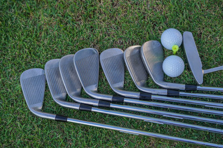 Golf equipment. Golf ball and golf club on green grass background. Collection of golf equipment resting on green grass. Outdoor sport.の写真素材