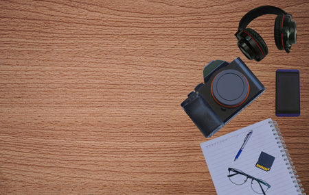 Office desk table with headphones, mobile phone, camera on wooden background. Business template mock up for adding your text. Top view with copy space.の写真素材