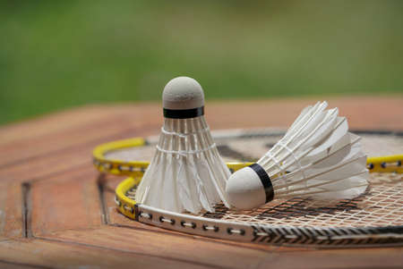 Two shuttlecocks and badminton racket. Badminton racket and shuttlecock closeup on the wooden court background.の写真素材
