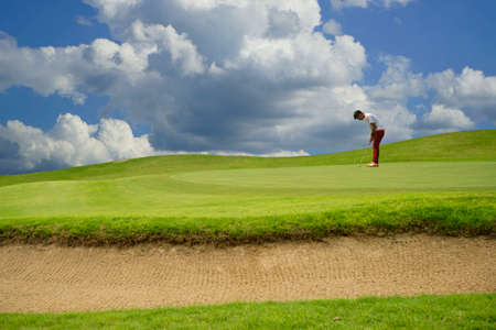 Golfers putting golf balls on the golf course in the morning. Golf man putting on green for birdie on the green golf.の写真素材