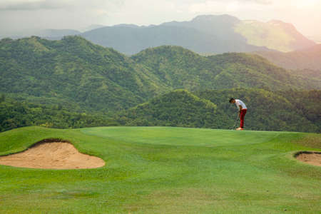 Golfers putting golf balls on the golf course in the morning. Golf man putting on green for birdie...