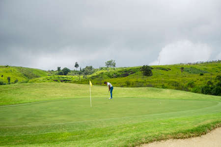 Golfer playing golf in the evening golf course, on sun set evening time. Male professional golfer playing golf on a beautiful course during the day.の写真素材
