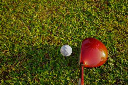 Golf ball and Blurred golf club close up in grass field with sunset. Golf ball close up in golf coures at Thailandの写真素材