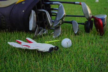 Hand holding golf ball with tee on course, tee off, copy space on Right side. Hand ware leather glove putting golf ball on tee off, black color backgroundの写真素材