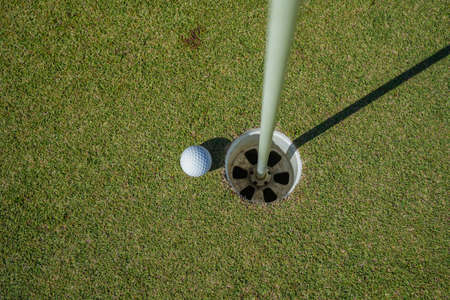 Golf clubs and golf balls on a green lawn in a beautiful golf course with morning sunshine. golf ball on green grass ready to hit on golf course background.の写真素材