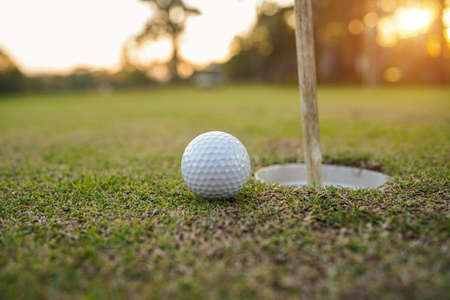 Golfer practice training putting golf ball on the green, lens flare on sun set evening time.の写真素材