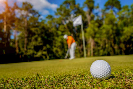 Golf ball is on a green lawn in a beautiful golf course with morning sunshine.Ready for golf in the first short.Sports that people around the world play during the holidays for health.の写真素材