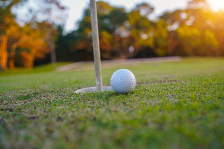 Golf ball is on tee at green lawn in a beautiful golf course with morning sunshine.Ready for golf in the first short.Sports that people around the world play during the holidays for health.の写真素材