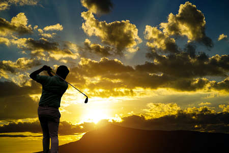 silhouette golfer playing golf during beautiful sunset. Golfer swinging club in Silhouette at Sunrise.の写真素材