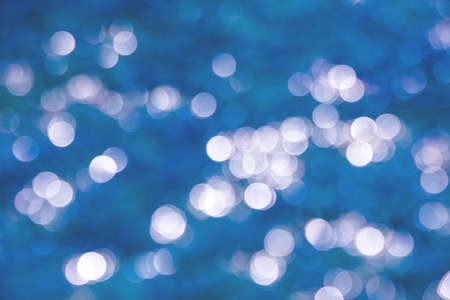 Abstract background of cold winter blue bokeh defocused blurred lights on background and glitter sparklesの写真素材