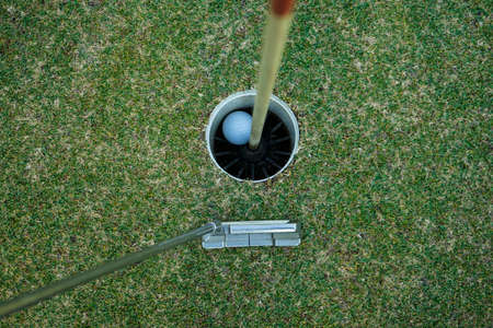Golf ball in the hole, Golf hole and golf ball on green grass on golf course, a golf ball sits in the cup with green aroundの写真素材