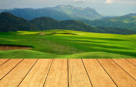 Wooden floor and golf course background. Fresh spring green golf course with wood floor. Beauty natural background, Empty wooden deck table with Green background.の写真素材