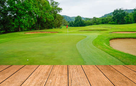 Wooden floor and golf course background. Fresh spring green golf course with wood floor. Beauty natural background, Empty wooden deck table with Green background.の写真素材