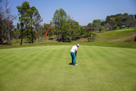 Golfer playing golf in the evening golf course, on sun set evening time. Man playing golf on a golf course in the sun.の写真素材