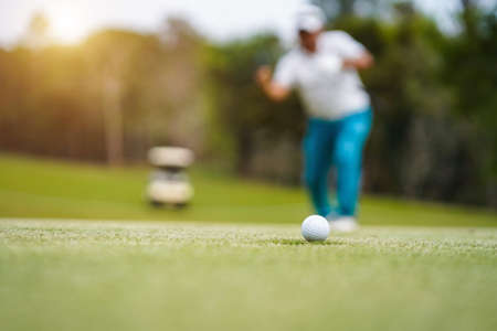 Golf balls that are going to be hole by golfers at the green grass golf course at sunset. Golfers are putting golf in the evening golf course, on sun set evening time.の写真素材