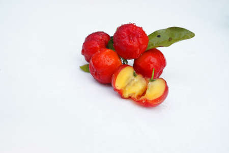 Fresh acerola fruit, typical from Brazil. Red organic Acerola Cherry with half slice and green leaves isolated on white background, High vitamin C and Antioxidant fruitsの写真素材