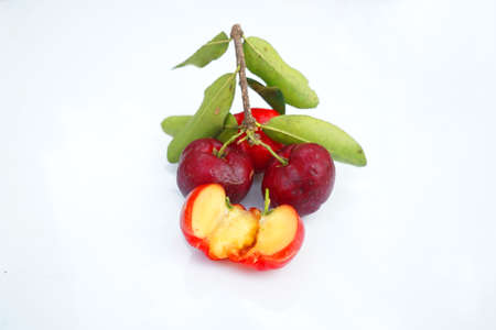 Fresh acerola fruit, typical from Brazil. Red organic Acerola Cherry with half slice and green leaves isolated on white background, High vitamin C and Antioxidant fruitsの写真素材