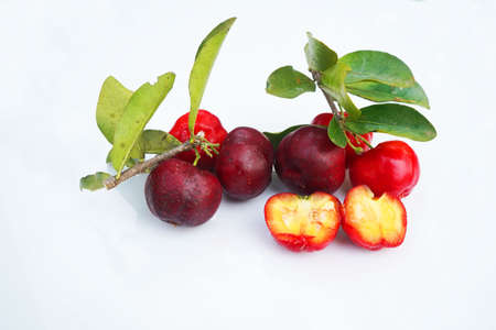Fresh acerola fruit, typical from Brazil. Red organic Acerola Cherry with half slice and green leaves isolated on white background, High vitamin C and Antioxidant fruitsの写真素材