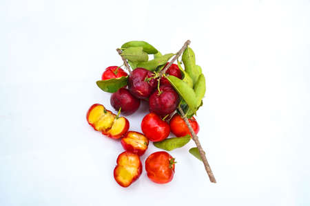 Fresh acerola fruit, typical from Brazil. Red organic Acerola Cherry with half slice and green leaves isolated on white background, High vitamin C and Antioxidant fruitsの写真素材