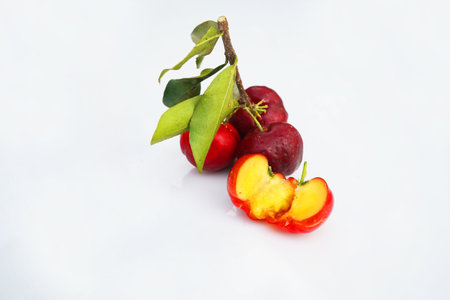 Fresh acerola fruit, typical from Brazil. Red organic Acerola Cherry with half slice and green leaves isolated on white background, High vitamin C and Antioxidant fruitsの写真素材