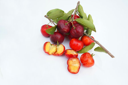 Fresh acerola fruit, typical from Brazil. Red organic Acerola Cherry with half slice and green leaves isolated on white background, High vitamin C and Antioxidant fruitsの写真素材