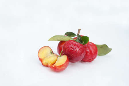 Fresh acerola fruit, typical from Brazil. Red organic Acerola Cherry with half slice and green leaves isolated on white background, High vitamin C and Antioxidant fruitsの写真素材
