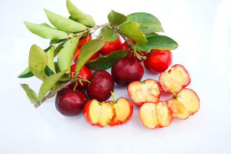 Fresh acerola fruit, typical from Brazil. Red organic Acerola Cherry with half slice and green leaves isolated on white background, High vitamin C and Antioxidant fruitsの写真素材