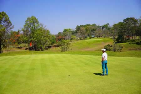 Asian golfer looking to target flag hole before swing golf.の写真素材