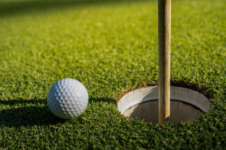 Close-up of golf ball on tee in beautiful golf course at sunset background. Ready for golf in the first short.の写真素材