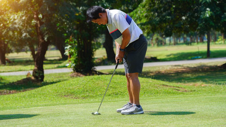 Golfer putting ball on the green golf, lens flare on sun set evening time, Golfer action to win after long putting golf ball in to the hole,の写真素材