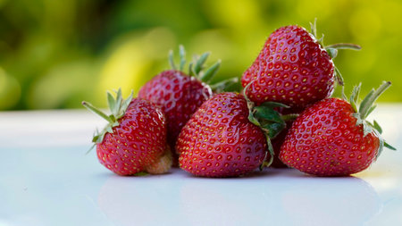 Red strawberries on white wooden table and farmland backgroundの写真素材