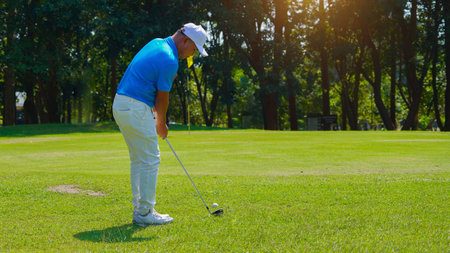 Golfer playing golf in the evening golf course, on sun set evening time, Man playing golf on a golf course in the sun.の写真素材