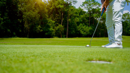 Golf balls that are going to be hole by golfers at the green grass golf course at sunset. Golfers...