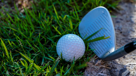 Golf balls and clubs in the obstacle zone of the course. Golf ball is on green lawn in a beautiful golf course with morning sunshine.の写真素材