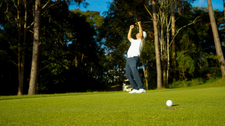 Golfer putting ball on the green golf, lens flare on sun set evening time. Golfer action to win...